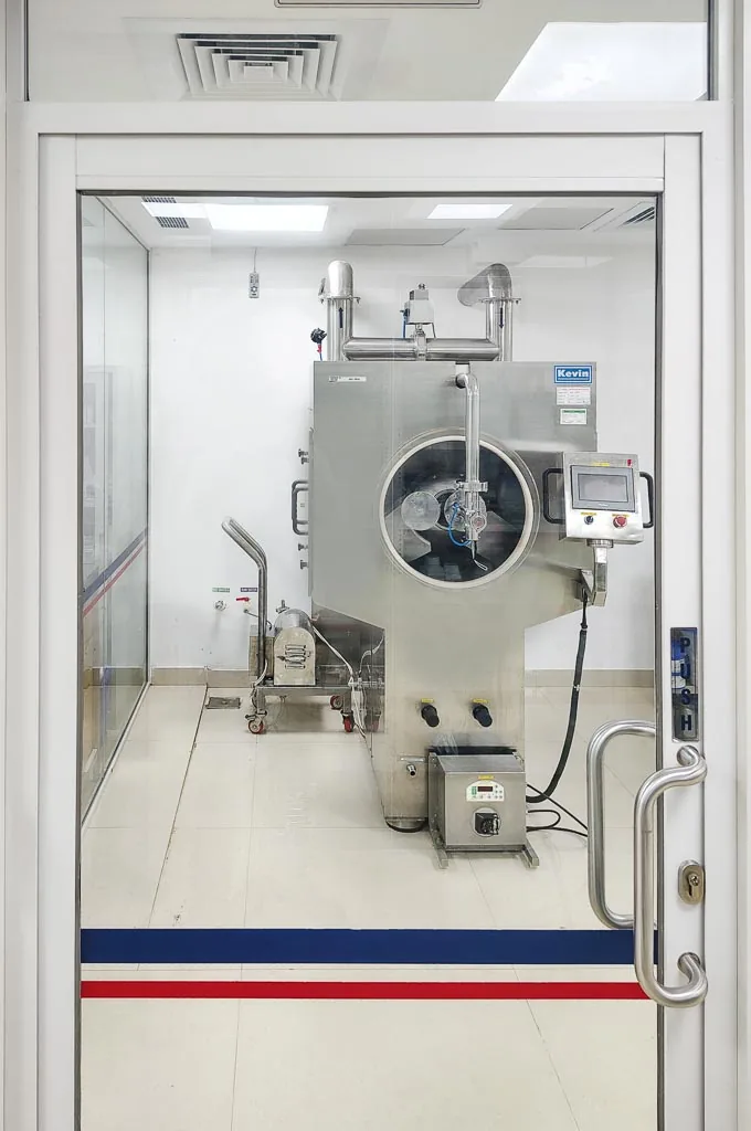 Automatic tablet coating machine in the Stabicon coating suite, viewed through the cleanroom door